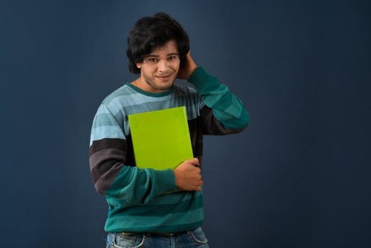 Young happy man holding and posing with the book on background. photo