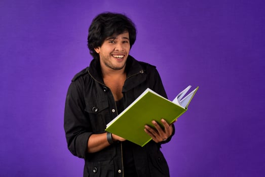 Young happy man holding and posing with the book on background. photo