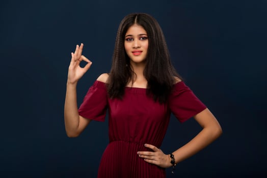 Young smiling girl showing okay sign or thumbs up on a gray background photo