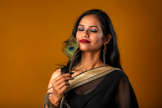 Beautiful Young Girl with bright makeup posing with peacock feathers on yellow background. photo
