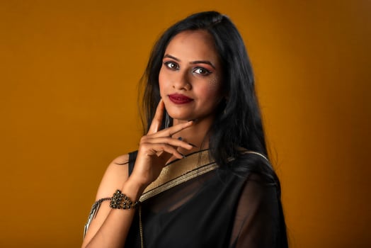 Portrait of a young beautiful girl wearing traditional black saree posing on a brown background. photo