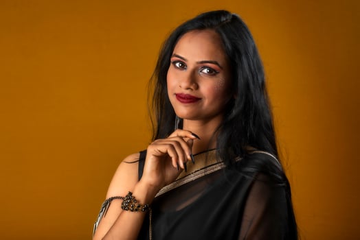 Portrait of a young beautiful girl wearing traditional black saree posing on a brown background. photo