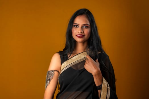 Portrait of a young beautiful girl wearing traditional black saree posing on a brown background. photo