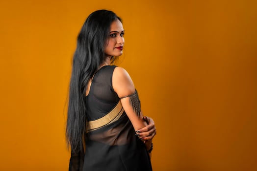 Portrait of a young beautiful girl wearing traditional black saree posing on a brown background. photo