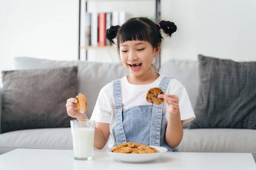 A young girl is eating cookies and drinking milk photo