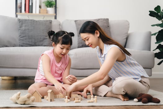 A woman and a little girl are playing with wooden blocks on a carpeted floor photo