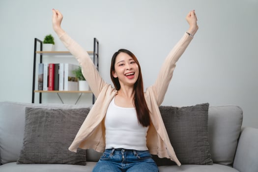 A woman is sitting on a couch and is smiling photo