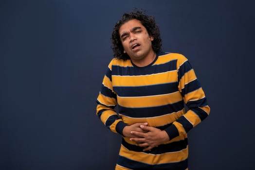 Unhappy man suffering from stomach ache over gray background. People, healthcare, and health problem concept. photo