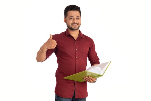 Young happy man holding and posing with the book on white background. photo