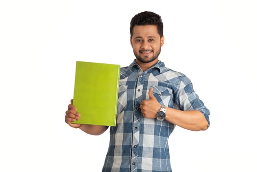 Young happy man holding and posing with the book on white background. photo