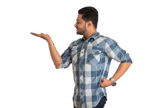 Portrait of a successful cheerful young man holding and presenting something on hand with a happy smiling face. photo