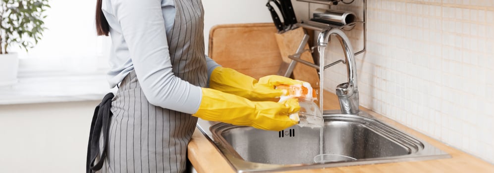 Chores Concept. Beautiful young woman in apron washing glass bowl in modern kitchen, copyspace photo