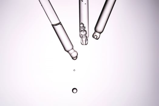 Three pipettes with a cosmetic product. Serum or fluid drips from one of them. photo
