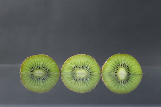 two or three circles of green kiwi semicircle with a black glossy still life photo