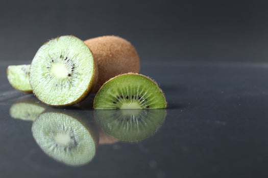 A few three pieces of kiwi lie in a pile on a black background with a copy space photo