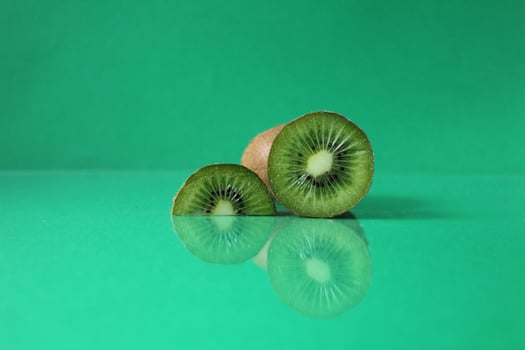 half and a circle of kiwi kusrchek with reflection on a green background with a copyspace photo