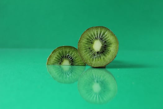 half and a circle of kiwi kusrchek with reflection on a green background with a copyspace photo