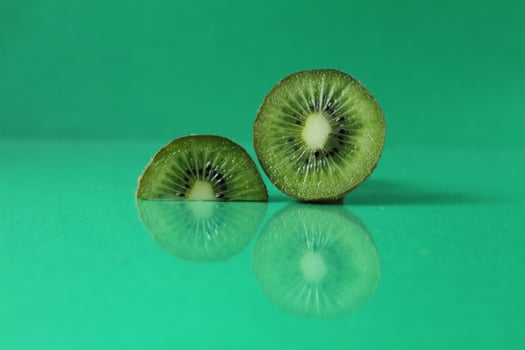 half and a circle of kiwi kusrchek with reflection on a green background with a copyspace photo