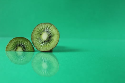 half and a circle of kiwi kusrchek with reflection on a green background with a copyspace photo