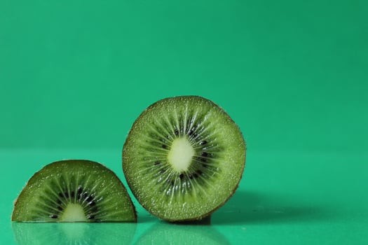 half and a circle of kiwi kusrchek with reflection on a green background with a copyspace photo