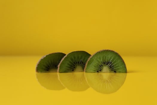 Three slices of kiwi halves lie in a row on trend iluminaited yellow with a copy of the space place for text photo