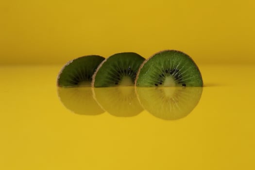 Three slices of kiwi halves lie in a row on trend iluminaited yellow with a copy of the space place for text photo