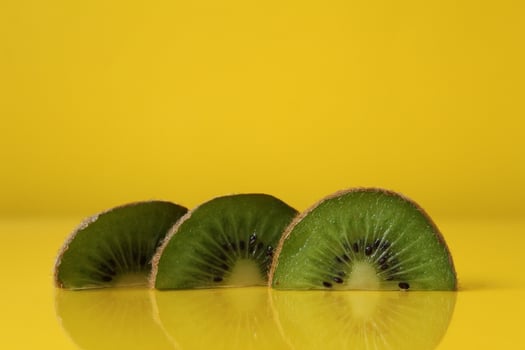 Three slices of kiwi halves lie in a row on trend iluminaited yellow with a copy of the space place for text photo
