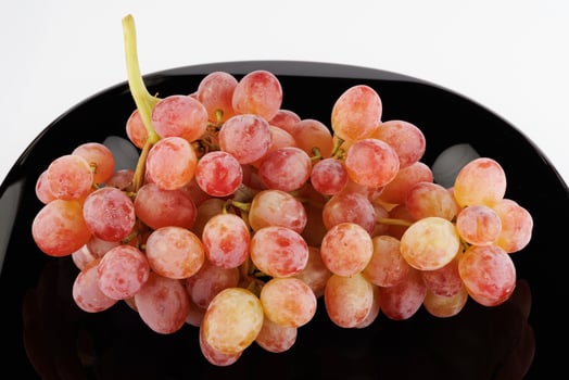 A juicy beautiful bunch of grapes lies in a black plate. photo