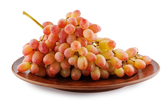 Juicy beautiful bunch of grapes lying in a clay plate isolated on a white background. photo