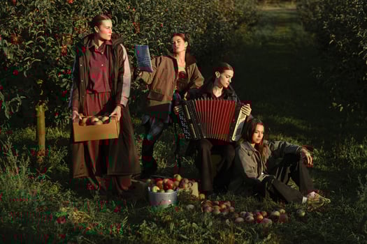 Four fashionable country girls at the apple harvest in the orchard. Happy girls playing accordion after apple harvest in an autumn orchard photo