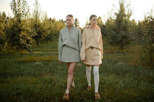 Two models in stylish tracksuits pose in apple orchard at sunset . The model is wearing a light-colored tracksuit and skirt photo