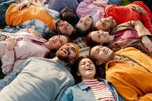 Diverse group of friends lying in circle on grass enjoying sunny day photo