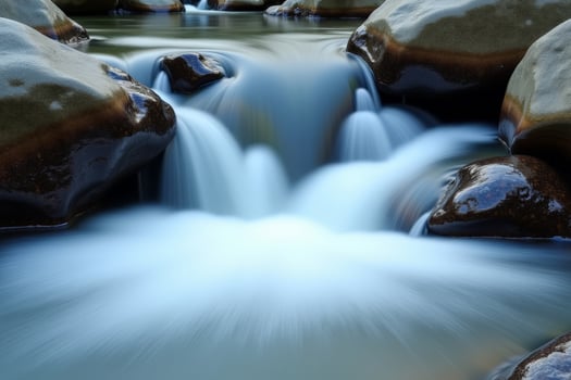 A stream of water flowing over rocks in a river photo