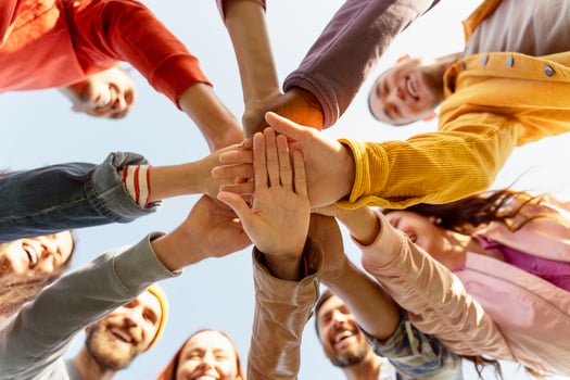 Group of people joining hands in a huddle smiling and bonding photo