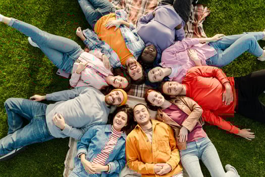 Group of diverse people lying in circle on grass having fun outdoors photo