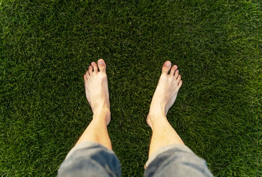 Man standing barefoot on green grass lawn photo