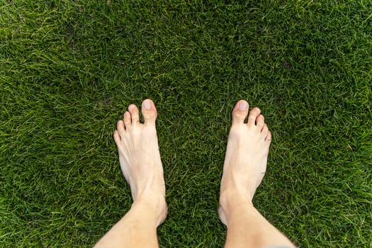 Man standing barefoot on green grass lawn texture background photo