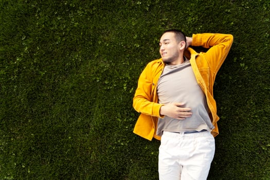 Young man relaxing lying down on green grass background photo