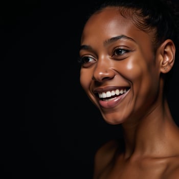 Closeup portrait of a youthful radiant African American woman with smooth skin and a bright smile gazing off into the distance on a dark backdrop photo