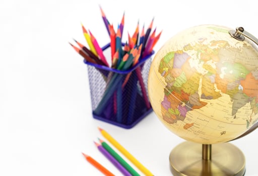 Focus globe and blur crayon or colored pencils behind in box on white background. Learning, study and education concept. photo