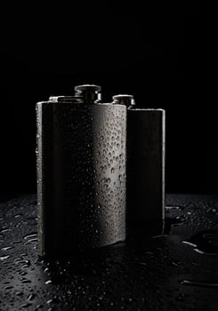 Stainless steel flasks on a black background with water drops. photo