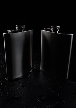 Two stainless steel flasks on a black background with water drops. photo