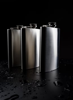 Stainless steel flasks on a black background with water drops. photo