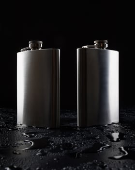 Two stainless steel flasks on a black background with water drops. photo