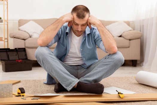 Confused Mature Man Having Hard Time Assembling Furniture Reading Self-Assembly Manual For Wooden Shelf Posing Sitting On Floor Indoor. Male Struggling Furnishing And Installing Furniture At Home photo