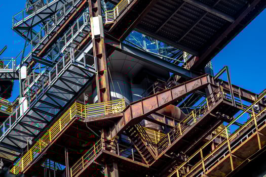 Rusty industrial building showing weathered metal structures under blue sky photo
