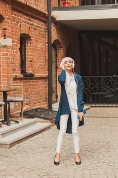 Portrait of young modern arabian woman holding mobile phone and listening the music to headphone. photo