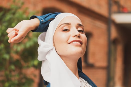 Portrait of young muslim woman wearing hijab head scarf in city while looking at camera. Closeup face of cheerful woman covered with headscarf smiling outdoor. Islamic girl outdoors. photo