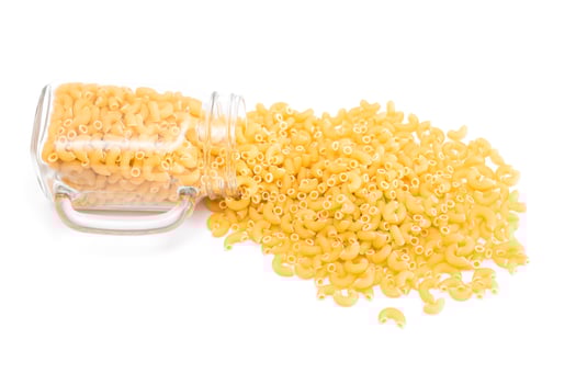 Uncooked Chifferi Rigati Pasta in Glass Jar Isolated on White Background. Fat and Unhealthy Food. Scattered Classic Dry Macaroni. Italian Culture and Cuisine. Raw Pasta photo