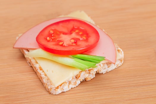 Rice Cake Sandwich with Tomato, Sausage, Green Onions and Cheese on Wooden Cutting Board. Easy Breakfast. Diet Food. Quick and Healthy Sandwiches. Crispbread with Tasty Filling. Healthy Dietary Snack photo
